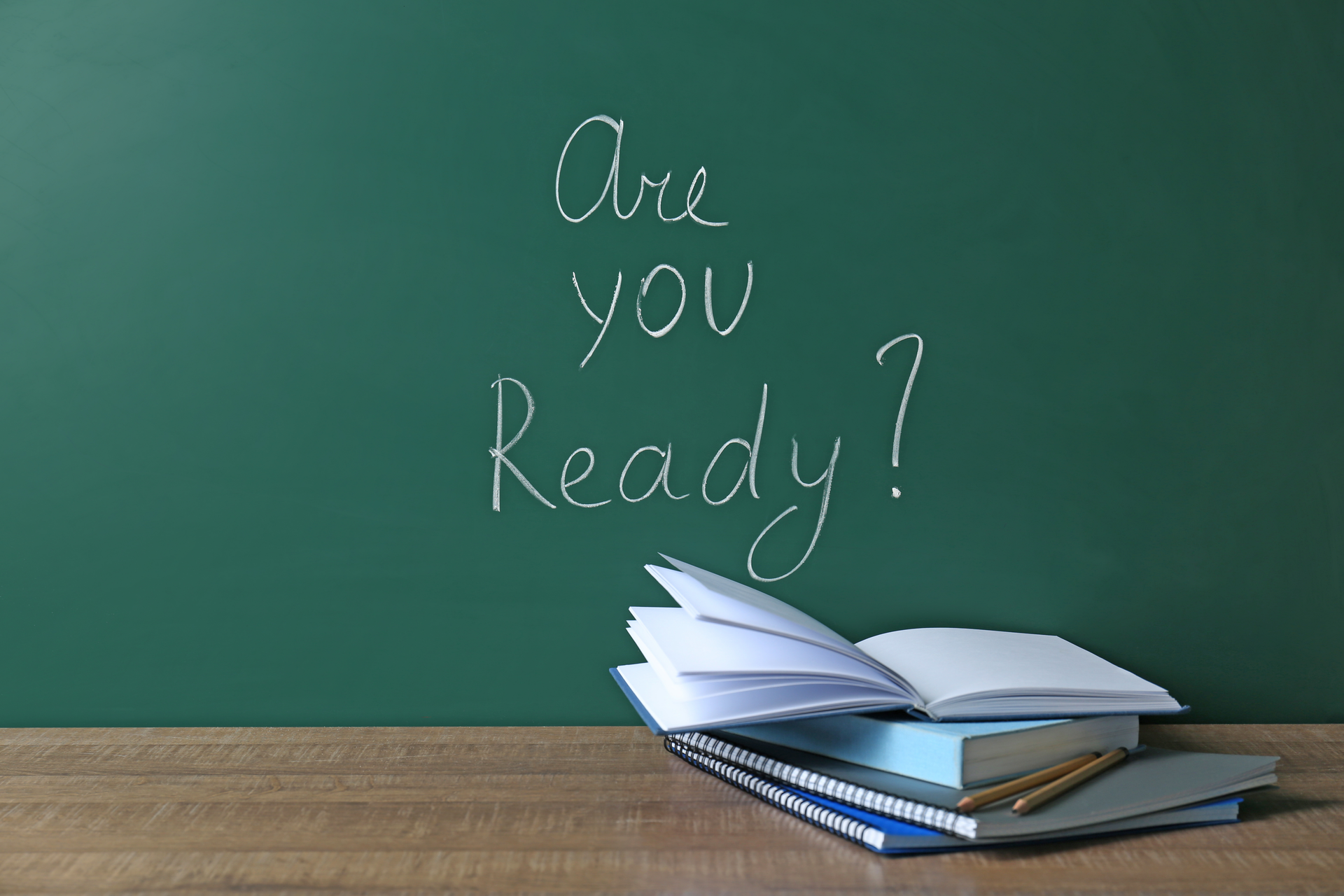 Chalkboard with question "Are you ready?" and notebooks on table.